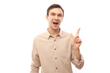 Üstü açık tişörtlü, beyaz saçlı yakışıklı esmer adam beyaz arka planda izole edilmiş ve fotokopi alanı olan boş bir yeri işaret ediyor. Ürünü gösteriyor, heyecan verici bir şey gösteriyor.