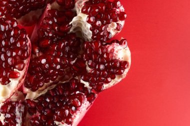 Kırmızı arka planda izole edilmiş taze, sulu, sulu, dilimlenmiş nar.