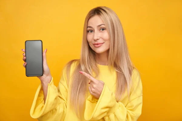 Vacker Blond Flicka Pekar Tom Telefonskärm Och Ler Isolerad Gul — Stockfoto