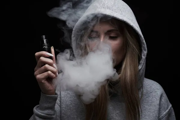 Portret Pięknej Blondynki Szarej Bluzie Kapturem Pali Vape Izolowane Czarnym — Zdjęcie stockowe