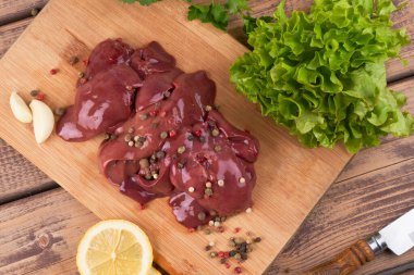 Tahtada çiğ tavuk ciğeri. Biber, limon ve bitkilerle çok güzel servis ediliyor.