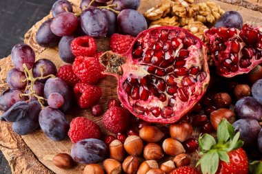 Tahta tepside servis edilen olgun taze meyve, meyve ve fındık.