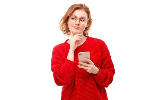 Menina Ruiva Sorridente Pensativa Segurando Smartphone Mãos Óculos Roupas Vermelhas — Fotografia de Stock