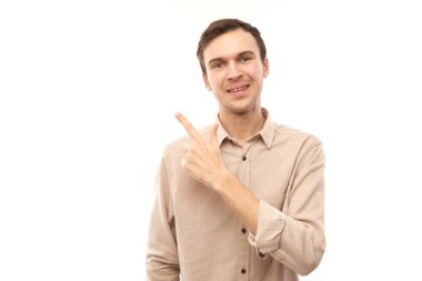 Üstü açık tişörtlü, beyaz saçlı yakışıklı esmer adam beyaz arka planda izole edilmiş ve fotokopi alanı olan boş bir yeri işaret ediyor. Ürünü gösteriyor, heyecan verici bir şey gösteriyor.