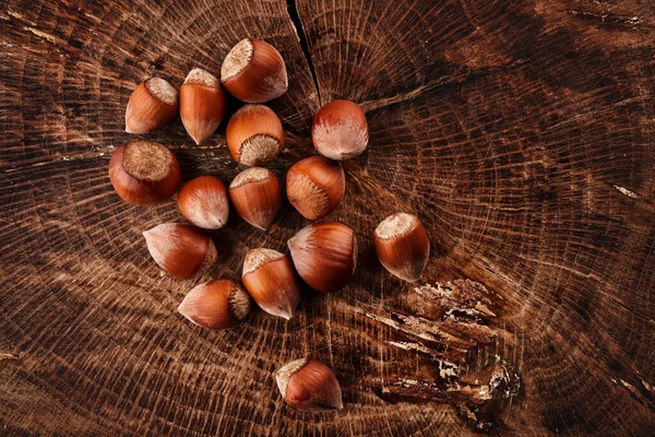 木の背景に隔離された殻の中のヘーゼルナッツのヒープ — ストック写真