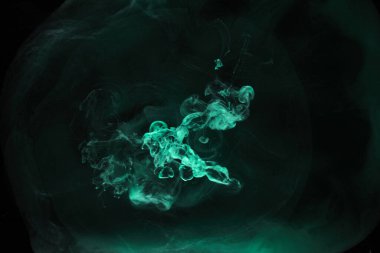 Siyah mürekkep arka planında yeşil duman, renkli sis, soyut girdaplı zümrüt okyanus denizi, su altında akrilik boya pigmenti