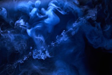 Siyah mürekkep arka planında mavi duman, renkli sis, soyut girdap gibi dönen okyanus denizi, akrilik boya pigmenti su altında.