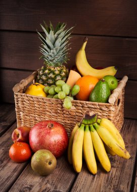 Tahta arka planda sepette taze renkli egzotik meyvelerin karışımı.
