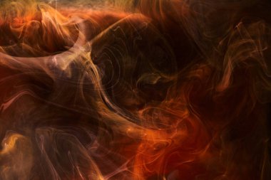 Siyah mürekkep arka planında turuncu duman, renkli sis, soyut girdap gibi dönen okyanus denizi, akrilik boya pigmenti su altında.