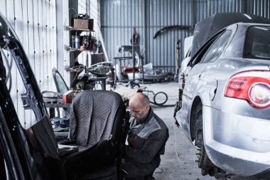 Araba tamircisi arabayı tamir ediyor.