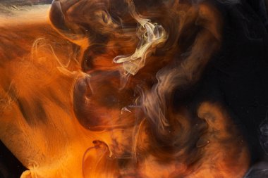 Siyah mürekkep arka planında turuncu duman, renkli sis, soyut girdap gibi dönen okyanus denizi, akrilik boya pigmenti su altında.