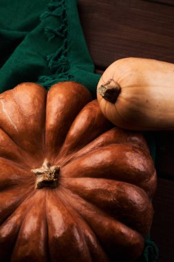 İki farklı olgun turuncu balkabağı ahşap arka planı kapatır.