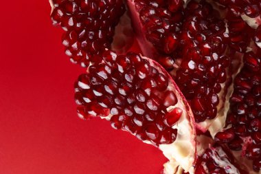 Kırmızı arka planda izole edilmiş taze, sulu, sulu, dilimlenmiş nar.