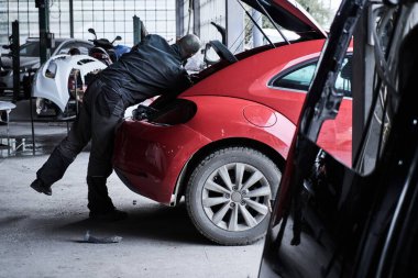 Araba tamircisi arabayı tamir ediyor.