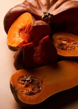 İki farklı dilimlenmiş olgun balkabağı yakın çekimli turuncu arka plan