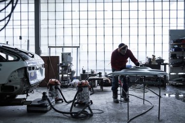 Araba tamircisi arabayı tamir ediyor.