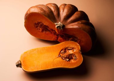 İki farklı dilimlenmiş olgun balkabağı yakın çekimli turuncu arka plan