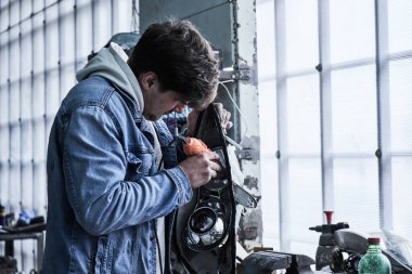 Araba tamircisi arabayı tamir ediyor.