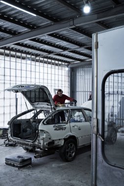 Araba tamircisi arabayı tamir ediyor.