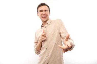 Dost canlısı, pozitif genç erkek portresi sizi seçer, beyaz arka planda izole edilmiş kamerayı işaret eder.