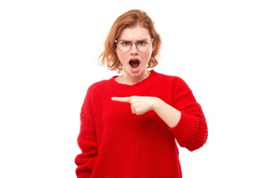 Şok olmuş kırmızı kazaklı kız beyaz stüdyo arka planında ağzı açık bir şekilde fotokopi makinesinde parmağını göstererek şaşırmış görünüyor.