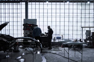 Araba tamircisi arabayı tamir ediyor.