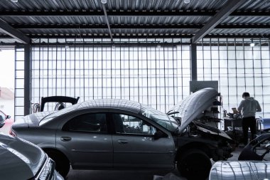 Araba tamircisi arabayı tamir ediyor.