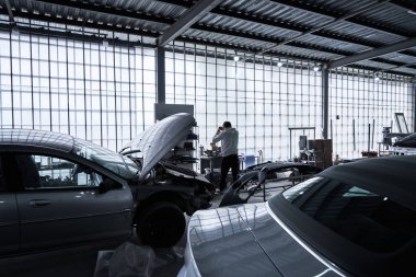 Araba tamircisi arabayı tamir ediyor.