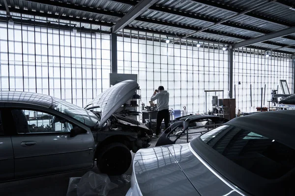 Araba tamircisi arabayı tamir ediyor.