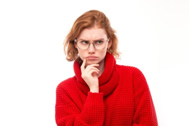 Kırmızılı ve çenesi gözlüklü akıllı kızıl saçlı kız kararlarını beyaz stüdyo arka planında belirliyor.