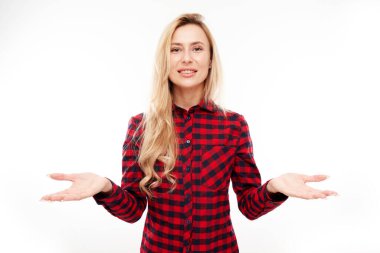 Çekici sarışın kız teşvikçi elinde bir şey tutarak boş bir alan gösteriyor. Heyecanlı yüzü beyaz arka planda izole edilmiş.