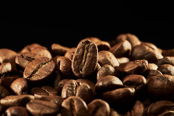 Kavrulmuş kahve çekirdekleri izole edilmiş. Siyah arka plana yakın, kırpma yolu.