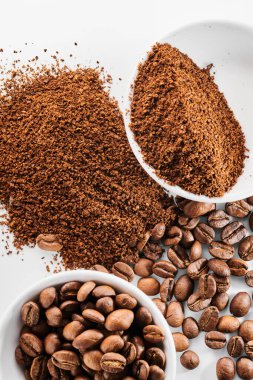 Kavrulmuş kahve ve kabın içindeki fasulye beyaz arka planda izole edilmiş.