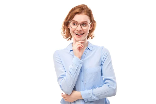 戴眼镜 身穿商务衫 聪明红头发的女孩满腹狐疑 在白色的工作室背景下做出了孤立的决定 — 图库照片
