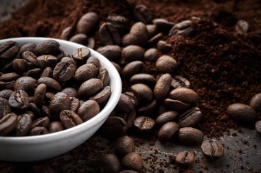 Kavrulmuş kahve ve kabın içindeki fasulye kahverengi grunge arka planına yakın izole edilmiş.