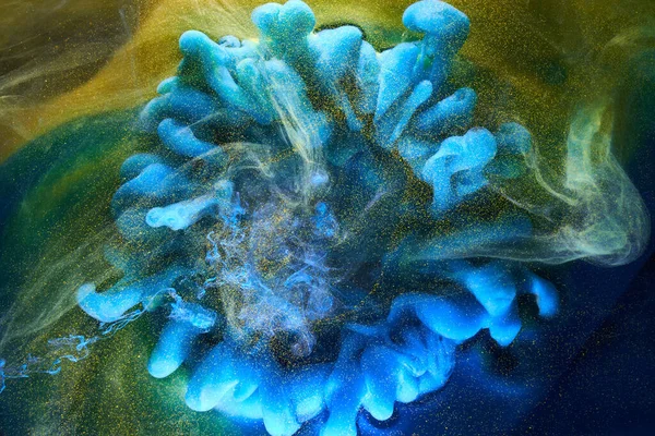 Sıvı akışkan sanat özgeçmişi. Mavi sarı dans eden akrilik boyalar suyun altında, okyanus dumanı