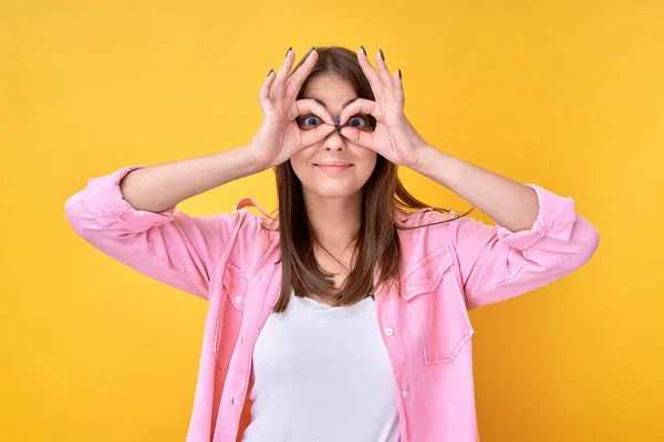 ポートレートのブルネット女の子作る眼鏡とともに指クソ周りに黄色の背景 — ストック写真