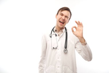 Beyaz önlüklü mutlu doktor portresi jestleri gösteriyor. Hepsi beyaz arka planda, fotokopi alanı ile izole edilmiş.