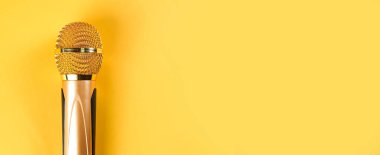 Sarı arka planda izole edilmiş altın mikrofon.