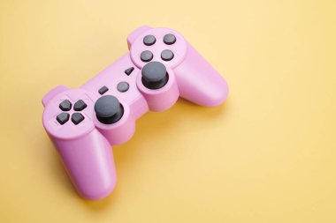 Pembe video oyun denetleyici, oyun konsolu için joystick sarı arka planda izole. Oyuncu kontrol aygıtı yakın plan