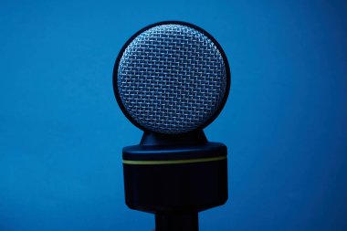 Mavi arkaplanda siyah mikrofon izole edildi.