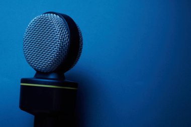 Mavi arkaplanda siyah mikrofon izole edildi.