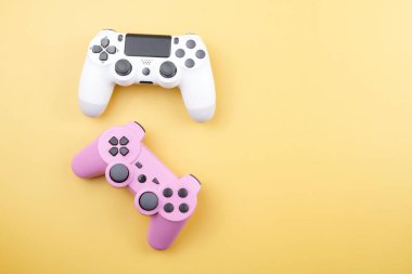İki oyun kumandası, oyun konsolu için oyun kumandası sarı arka planda izole edilmiş. Oyuncu kontrol cihazları yakın plan