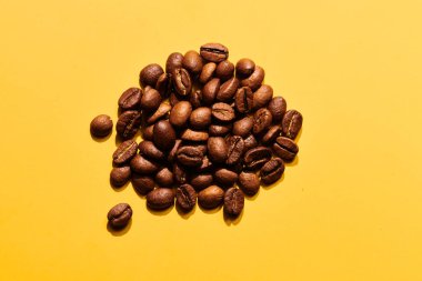 Sarı arka planda kızarmış kahve çekirdekleri.
