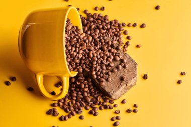 Sarı arka planda taze demlenmiş kahve çekirdekleri.