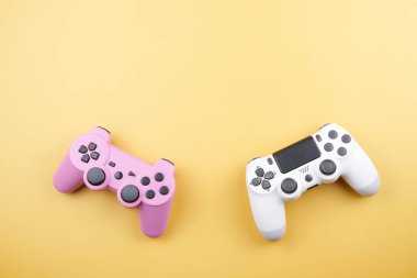İki oyun kumandası, oyun konsolu için oyun kumandası sarı arka planda izole edilmiş. Oyuncu kontrol cihazları yakın plan