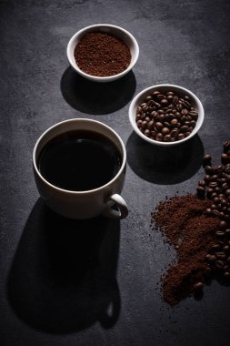 Beyaz kahve fincanı. Gri arka planda kavrulmuş kahve çekirdekleri.