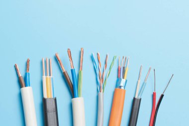 Elektrik kabloları, mavi arka planda izole edilmiş renkli izolasyonlu bir sürü bakır kablo.