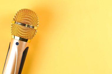 Sarı arka planda izole edilmiş altın mikrofon.