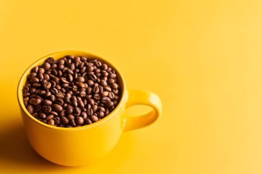 Sarı arka planda taze demlenmiş kahve çekirdekleri.